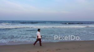 PD0902 - Aerial Tracking Shot of a Man Walking on a Beach