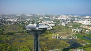 PD0958 - Aerial Drone Orbits Futuristic Tower Overlooking Coastal Cityscape