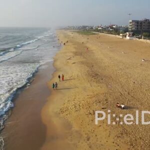 PD0944 - Drone Follows People Walking on a Scenic Urban Beach