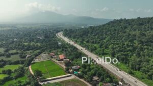 PD1036 - Aerial Drone Flight Over Highway Alongside Forested Mountain